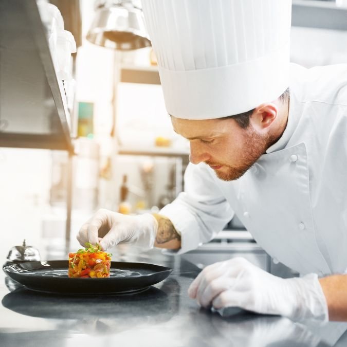 Cozinheiro preparando uma deliciosa comida vegana em um restaurante.