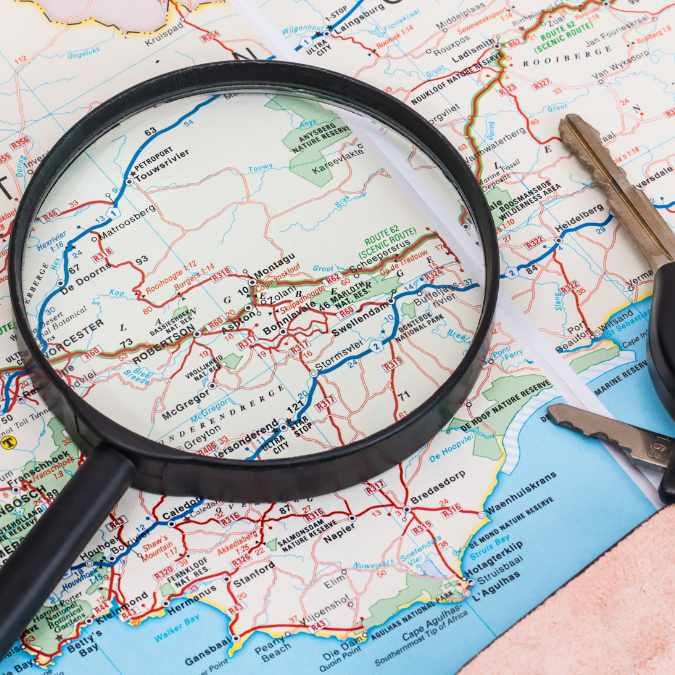 Navegador definindo rota no mapa com uma lupa focando em um local específico, simbolizando o foco e a importância de estabelecer prioridades.