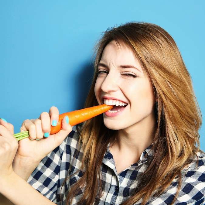 Mulher comendo cenoura.