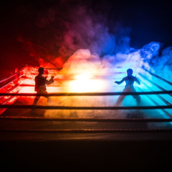 Garotos em uma luta de box. O tatame está envolvido por uma neblina, de um lado azul e do outro vermelho.