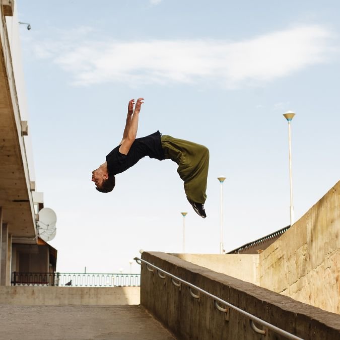 Jovem dando mortal ao praticar parkour.