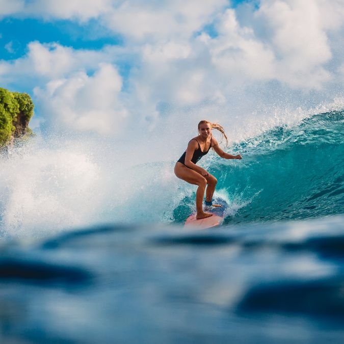 Mulher surfando onda.
