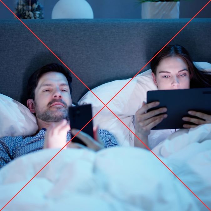 Casal usando telas na cama e sendo expostos a luz azul.